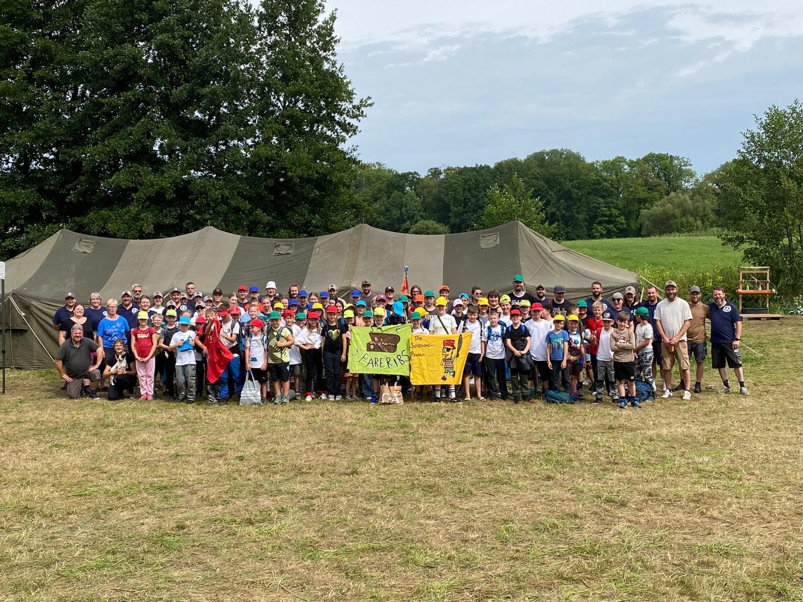 Großes Gruppenfoto der Lagergruppe vor olivgrünem Großzelt mit Piratenbannern